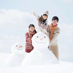 雪だるまの側で微笑む家族