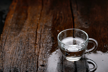 water in cup on wooden background 