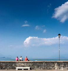 women sitting on the wall in front of the sea