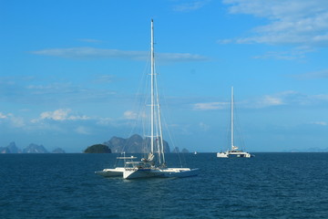 Two white yachts in the blue sea against the blue sky.