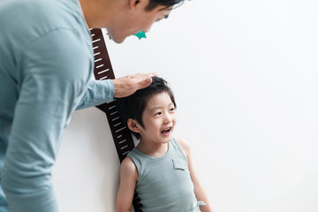 Dad in measuring height for the little boy