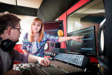Music engineer and musician working together in recording studio using mixing desk
