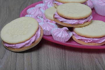 Cooked marshmallow sandwiches. They lie on plate. Next on the plate is a marshmallow of various sizes.