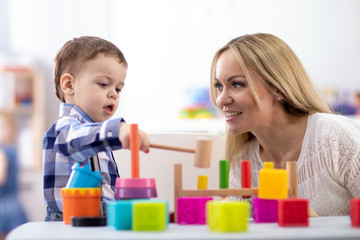Obraz na płótnie Canvas Nursery baby and mother or teacher play with montessori toys at table in daycare centre
