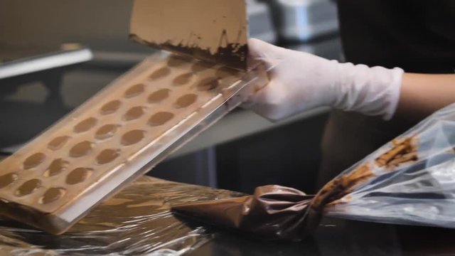 Pastry chef processing chocolate in kitchen.