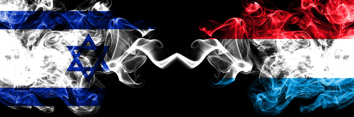 Israel vs Luxembourg smoky mystic flags placed side by side. Thick colored silky smokes flag of Israel and Luxembourg