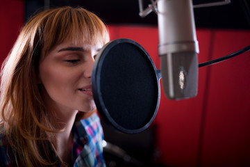 Female with microphone recording a voice for dubbing in music studio