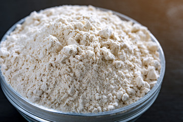 Composition with wheat grains, flour with heart shape on black background