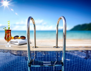 Cold summer beer and swimming pool background with beach 