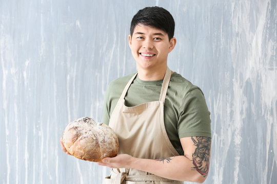 Asian Baker With Fresh Bread On Grey Background