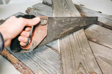 Man holding a saw. Old wooden planks.