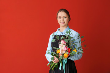 Female florist with bouquet on color background