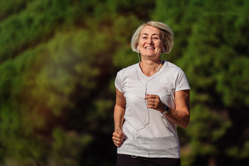 Senior woman jogging at sunrise. Morning running