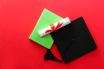 Mortar board, diploma and book on color background. Concept of high school graduation