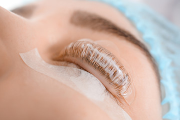 Young woman undergoing procedure of eyelashes lamination in beauty salon, closeup