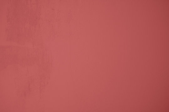 Pastellrote Betonwand mit verputzten Strukturen. Roter Hintergrund im Industrial Design. Strukturierte Steinwand als Textur und gestalterisches Element f&uuml;r Kunst und Kollagen. 