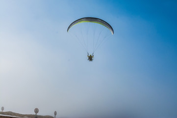 Parachutist flies against the blue sky. Motorized parachute