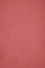 Pastellrote Betonwand mit verputzten Strukturen. Roter Hintergrund im Industrial Design. Strukturierte Steinwand als Textur und gestalterisches Element für Kunst und Kollagen. 