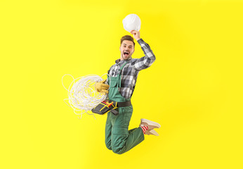 Jumping male electrician on color background