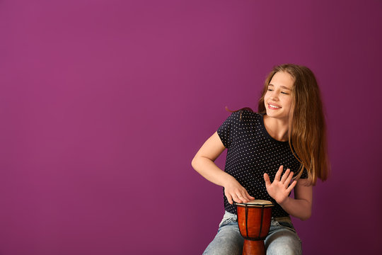 Teenage Girl Playing Drum Against Color Background