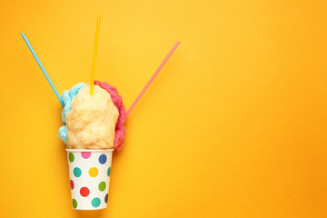 Cup with tasty cotton candy on color background