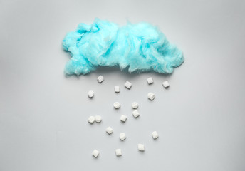 Tasty cotton candy cloud with sugar cubes on grey background