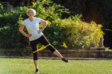 Mature sport woman training with fitness band in the park 