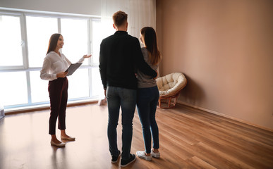 Real estate agent showing young couple a new house