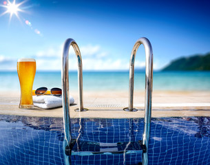 Fresh cold beer and swimming pool. Sea and beach landscape. 