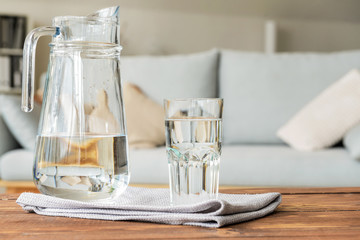 Glass and jug of fresh water on table