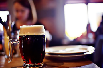 mug of dark beer in the interior of  pub / pint of beer with foam on a served table in  beer restaurant in Czech Republic