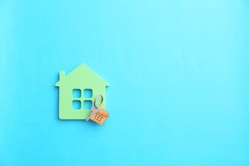 Figure of house and key on color background
