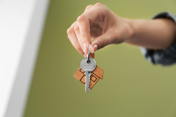 Female hand with key from house on color background
