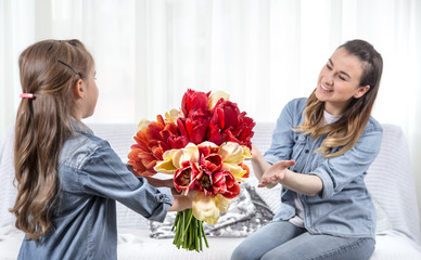 Mother's day. Little daughter with flowers congratulates her mother