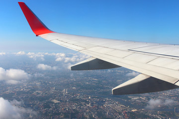 Fototapeta premium Airplane flying on blue sky and white cloud. Wing of an airplane flying above the cloud looks from the window of the plane. 