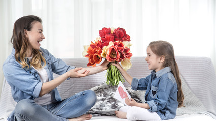 Mother's day. Little daughter with flowers congratulates her mother