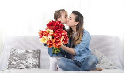 Mother's day. Little daughter with flowers congratulates her mother