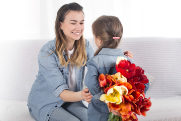 Mother's day. Little daughter with flowers congratulates her mother