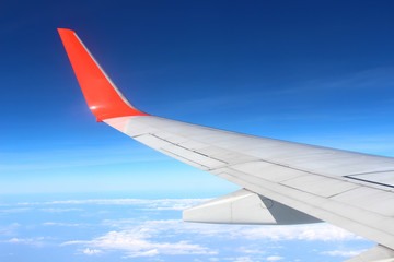 Obraz premium Airplane flying on blue sky and white cloud. Wing of an airplane flying above the cloud looks from the window of the plane. 