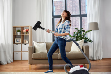 household, housework and cleaning concept - asian woman or housewife with vacuum cleaner having fun at home