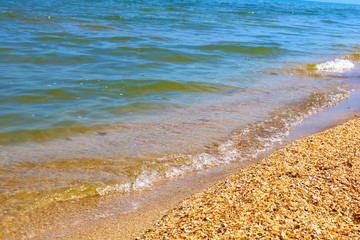 Little frothy waves of the sea on the sandy beach. Foamy wave rolls on the Golden sand of the beach. Detailed, abstract and simple background.