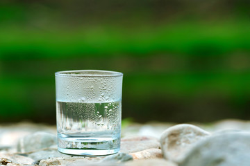 The glass of cool fresh water on nature background