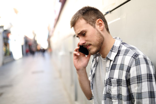 Sad man talks on phone in a solitary street