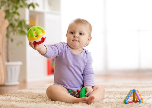 Baby playing on rug on the floor in nursery