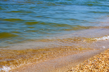 Little frothy waves of the sea on the sandy beach. Foamy wave rolls on the Golden sand of the beach. Detailed, abstract and simple background.
