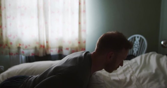 4K Exhausted or unwell Caucasian man collapsing face-down onto soft comfy bed. Slow motion.