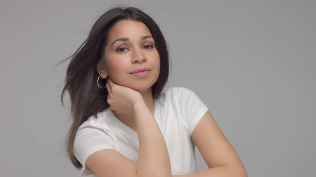 calm young mixed race woman looking to the camera. blowing hair slowmotion from 60 fps