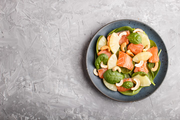 Fresh salmon with pineapple, spinach and cashew in blue ceramic plate on a gray concrete background.