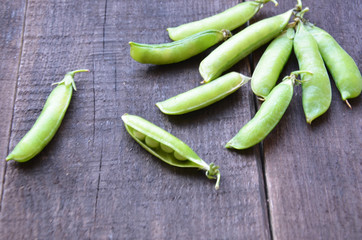 fresh green peas, just harvest. close up view of opened pod. spring vegetable up view on the wooden background