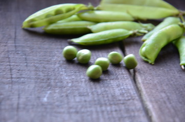 fresh green peas, just harvest. close up view of opened pod. spring vegetable up view on the wooden background